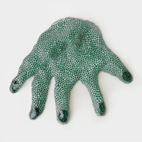 main en porcelaine couverte de multiples points verts